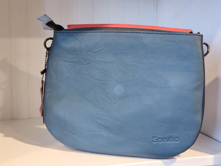 Blue handbag with a visible brand logo on a white surface.
