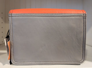 Close-up of an orange leather wallet with 'Soruka' branding on a light surface.