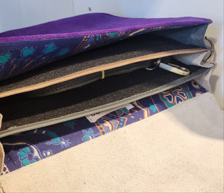 Purple fabric pouch with a pattern, held open to reveal its interior.