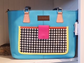 Blue tote bag with houndstooth pattern pocket and pink flap on a white surface.