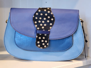 Blue handbag with a polka dot strap on a white surface